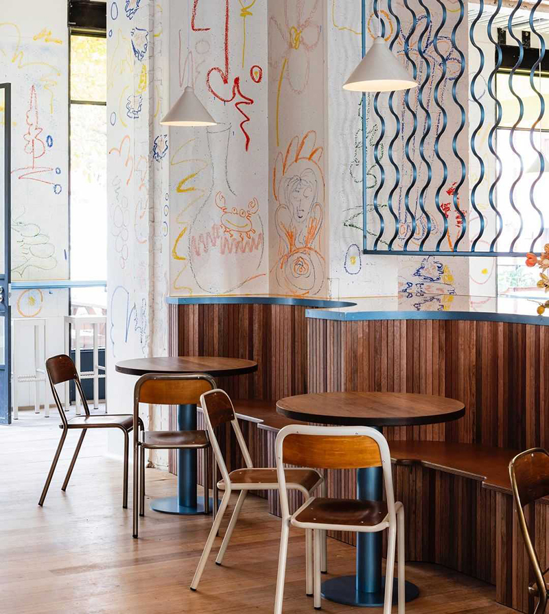 Tables and chairs inside Hope St Restaurant with welcoming wooden booths, a playful mural and other architectural and design elements